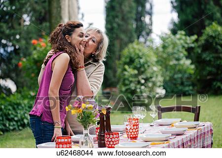 Picture - Woman kissing granddaughter at table for family meal. Fotosearch
