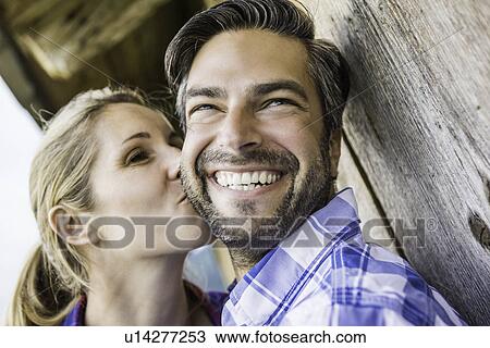 Woman kissing man's cheek outside wooden shack View Large Photo Image Stock Image - Woman kissing man's cheek outside wooden shack. Fotosearch