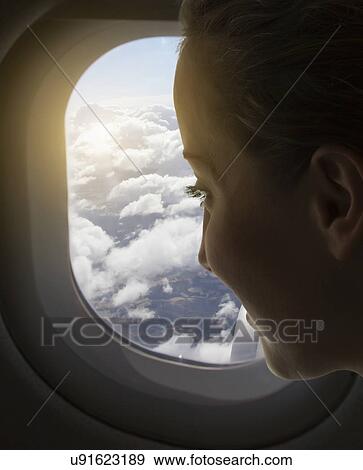 Woman looking out of airplane window View Large Photo Image Stock Photo - Woman looking out of airplane window. Fotosearch