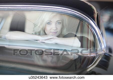 Stock Image - Woman looking out of rear car windscreen. Fotosearch