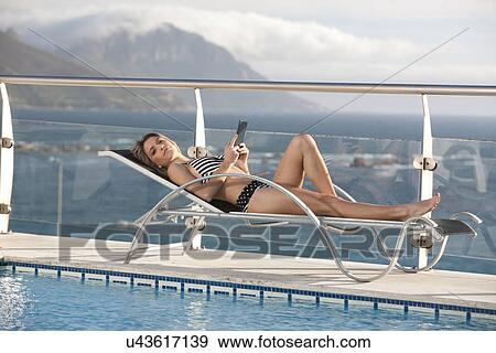 Woman relaxing by swimming pool, Cape Town, South Africa View Large Photo Image Stock Photo - Woman relaxing by swimming pool, Cape Town, South Africa. Fotosearch