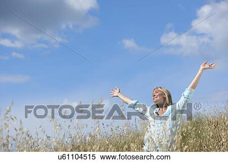 Woman standing in corn field with arms raised View Large Photo Image Stock Photography - Woman standing in corn field with arms raised. Fotosearch