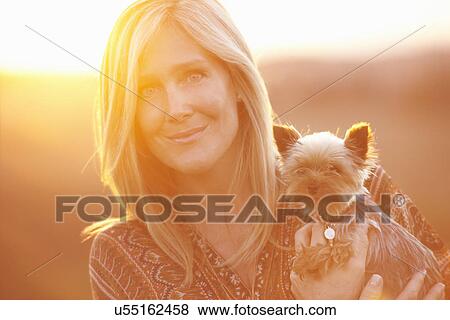 Woman standing in field at dusk holding domestic dog View Large Photo Image Stock Photo - Woman standing in field at dusk holding domestic dog. Fotosearch