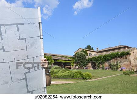 Woman standing outside house, covered by architects plans View Large Photo Image Picture - Woman standing outside house, covered by architects plans. Fotosearch