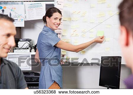 Woman sticking adhesive notes on whiteboard View Large Photo Image Stock Photo - Woman sticking adhesive notes on whiteboard. Fotosearch