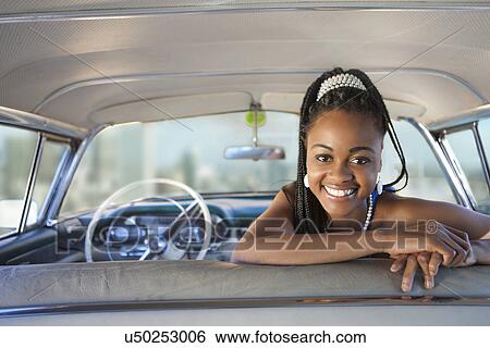 Stock Photograph - Woman turning around from front seat of vintage car. Fotosearch