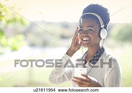 Woman wearing headphones listening to music View Large Photo Image Picture - Woman wearing headphones listening to music. Fotosearch