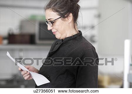 Woman working in restaurant kitchen, reading order View Large Photo Image Stock Image - Woman working in restaurant kitchen, reading order. Fotosearch