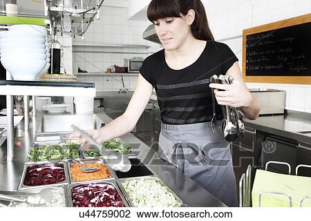 Woman working in restaurant kitchen, holding salad tongs View Large Photo Image Stock Image - Woman working in restaurant kitchen, holding salad tongs. Fotosearch