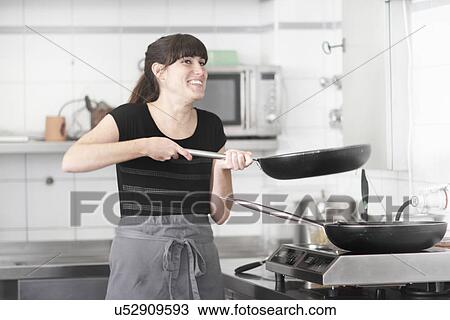 Woman working in restaurant kitchen, holding frying pan View Large Photo Image Stock Image - Woman working in restaurant kitchen, holding frying pan. Fotosearch
