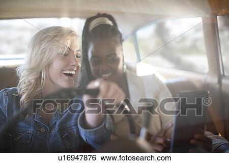 Women at wheels of vintage car laughing at message on digital tablet View Large Photo Image Stock Photograph - Women at wheels of vintage car laughing at message on digital tablet. Fotosearch