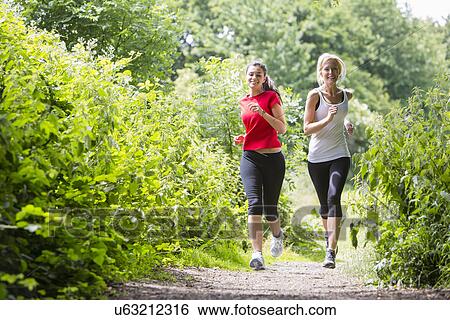Stock Photograph - Women jogging through forest. Fotosearch