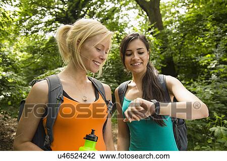 Stock Image - Women out walking in forest, checking the time. Fotosearch
