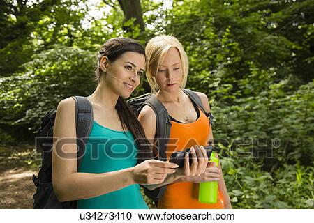 Women out walking in forest, looking at GPS View Large Photo Image Stock Image - Women out walking in forest, looking at GPS. Fotosearch