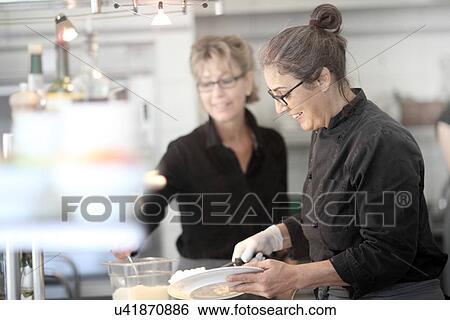 Stock Photograph - Women working in restaurant kitchen. Fotosearch