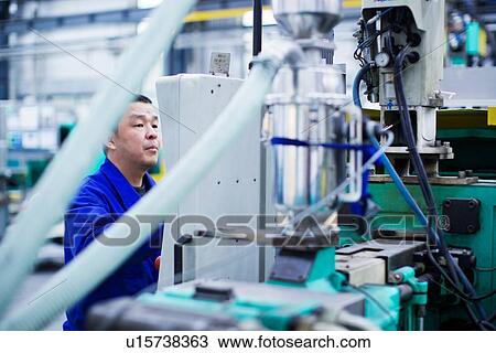 Stock Image - Worker at small parts manufacturing factory in China. Fotosearch