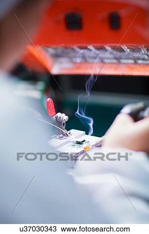 Stock Image - Worker at small parts manufacturing factory in China. Fotosearch