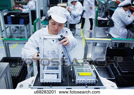 Stock Image - Worker at small parts manufacturing factory in China. Fotosearch