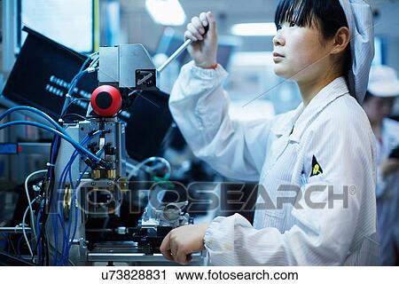 Stock Image - Worker at small parts manufacturing factory in China. Fotosearch
