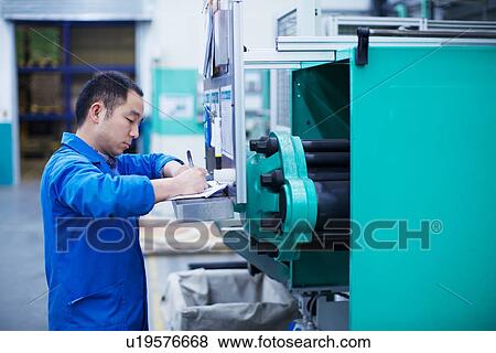 Stock Photo - Worker at small parts manufacturing factory in China, writing paperwork. Fotosearch