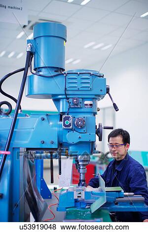 Stock Photo - Worker at small parts manufacturing factory in China. Fotosearch