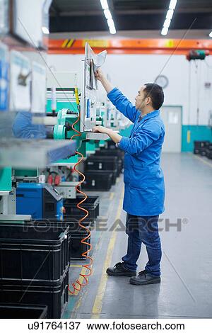 Worker at small parts manufacturing factory in China, reaching up to press button on control panel View Large Photo Image Stock Photo - Worker at small parts manufacturing factory in China, reaching up to press button on control panel. Fotosearch