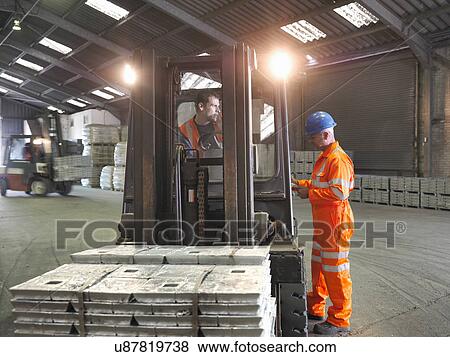 Worker checking delivery of metal alloy with fork lift driver in port store View Large Photo Image Stock Photo - Worker checking delivery of metal alloy with fork lift driver in port store. Fotosearch