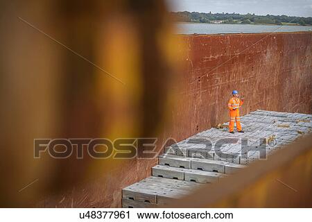 Worker checking metal ingots in ship's hold View Large Photo Image Stock Image - Worker checking metal ingots in ship's hold. Fotosearch