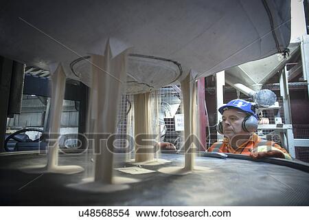 Worker in hard hat and ear defenders inspecting zircon sand View Large Photo Image Picture - Worker in hard hat and ear defenders inspecting zircon sand. Fotosearch