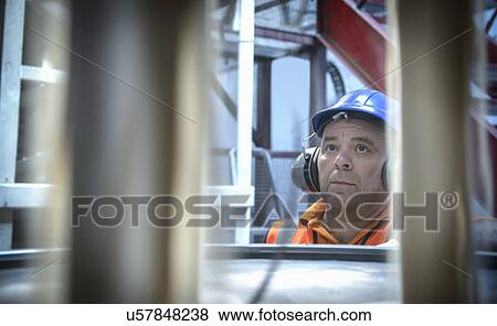 Worker in hard hat and ear defenders inspecting zircon sand View Large Photo Image Stock Photo - Worker in hard hat and ear defenders inspecting zircon sand. Fotosearch