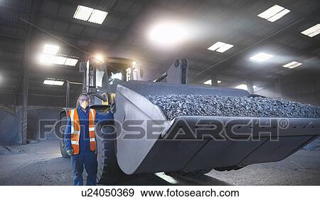 Worker in mineral store next to digger full of metal alloy View Large Photo Image Stock Photo - Worker in mineral store next to digger full of metal alloy. Fotosearch