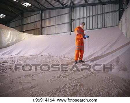 Worker in reflective clothing inspecting zircon sand View Large Photo Image Picture - Worker in reflective clothing inspecting zircon sand. Fotosearch