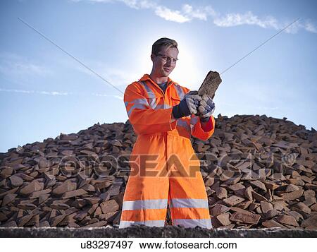 Stock Photo - Worker in reflective clothing inspecting pig iron. Fotosearch