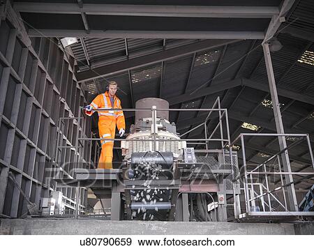 Worker in reflective workwear operating metal crushing machine View Large Photo Image Stock Photo - Worker in reflective workwear operating metal crushing machine. Fotosearch