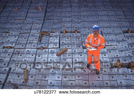 Worker in reflective workwear standing on metal alloy cargo in ship's hold, portrait View Large Photo Image Stock Photo - Worker in reflective workwear standing on metal alloy cargo in ship's hold, portrait. Fotosearch