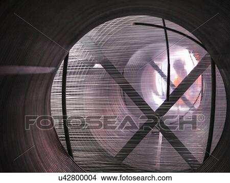 Picture - Worker looking through packaged coils of wire. Fotosearch