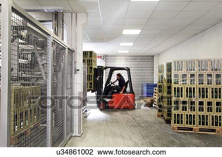 Stock Image - Worker on forklift moving cases of wine. Fotosearch