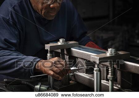 Stock Photo - Worker setting up a rack bar to be machined. Fotosearch