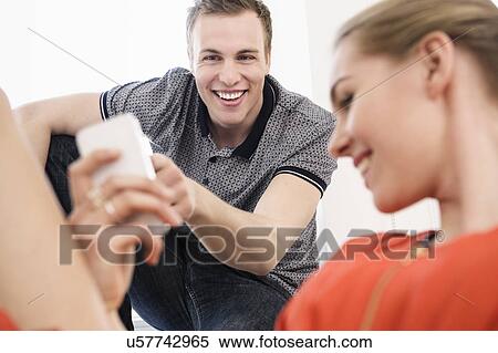 Young adult couple laughing at mobile phone View Large Photo Image Stock Photography - Young adult couple laughing at mobile phone. Fotosearch