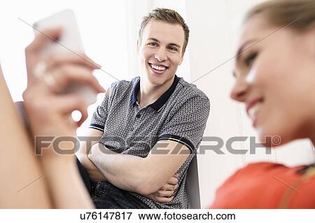 Stock Photo - Young adult couple looking at mobile phone. Fotosearch