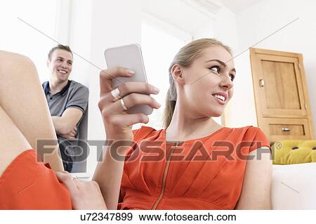Young adult couple lounging in sitting room with mobile View Large Photo Image Stock Photo - Young adult couple lounging in sitting room with mobile. Fotosearch