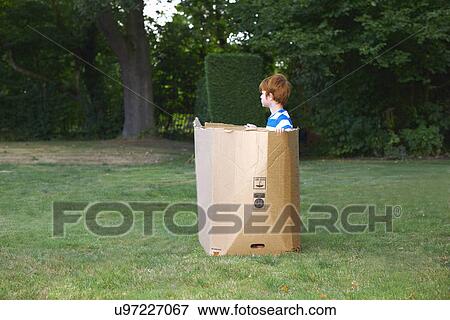 Young boy watching from cardboard box in garden View Large Photo Image Stock Photo - Young boy watching from cardboard box in garden. Fotosearch