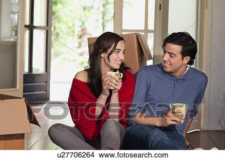 Picture - Young couple having coffee break whilst moving house. Fotosearch
