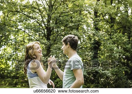 Young couple holding hands in park View Large Photo Image Stock Image - Young couple holding hands in park. Fotosearch
