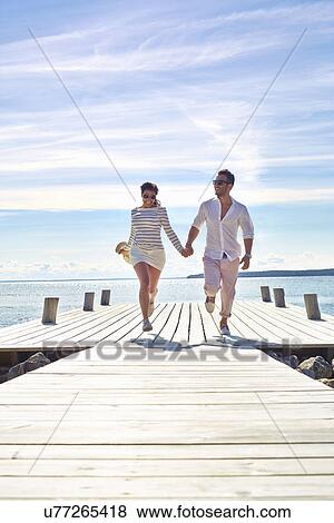 Young couple holding hands on pier, Gavle, Sweden View Large Photo Image Stock Photo - Young couple holding hands on pier, Gavle, Sweden. Fotosearch
