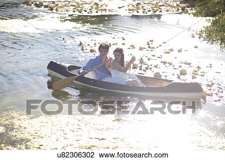Stock Image - Young couple in rowing boat on river. Fotosearch