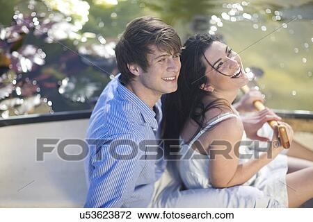 Stock Image - Young couple laughing in rowing boat. Fotosearch