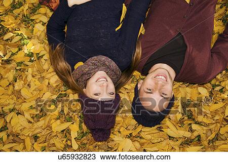 Stock Image - Young couple lying in autumn leaves. Fotosearch