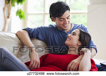 Young couple reclining on living room sofa View Large Photo Image Stock Photo - Young couple reclining on living room sofa. Fotosearch