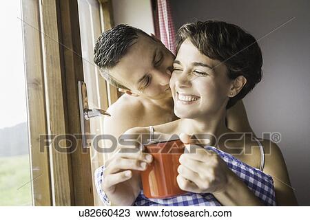 Stock Image - Young couple sharing a kiss in holiday chalet, Tyrol, Austria. Fotosearch